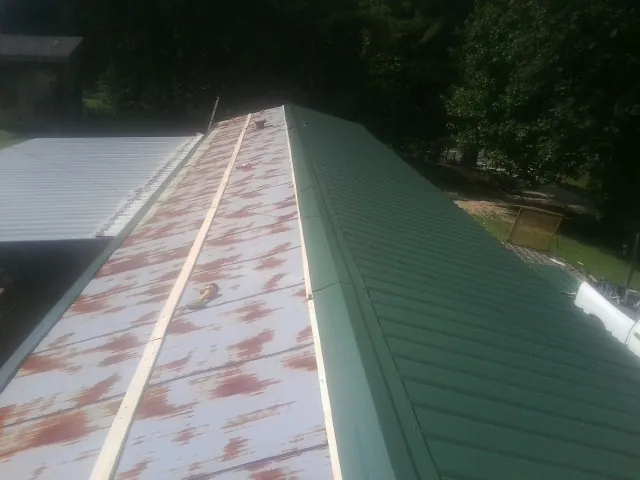 Old rusted panels beside newly installed green metal roofing — Wind Damage Roof Repair by Roofing Brothers in Walled Lake