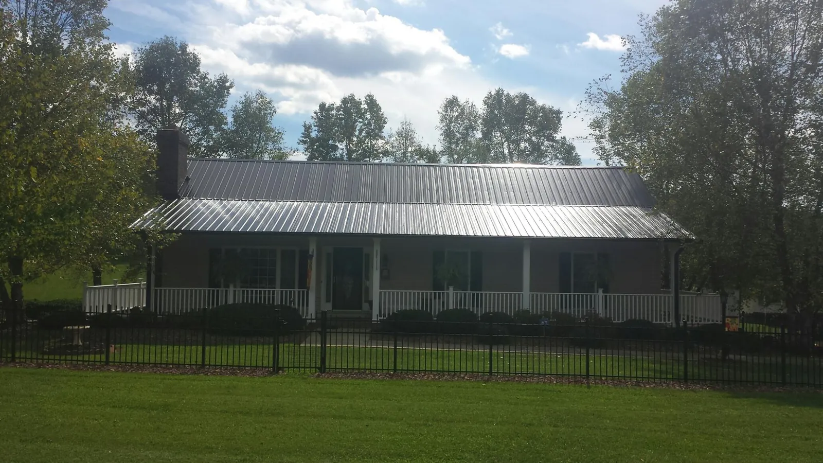 Gray metal roof on a brick ranch with a full width front porch — Gutter Guard Installation work by our crew in Walled Lake