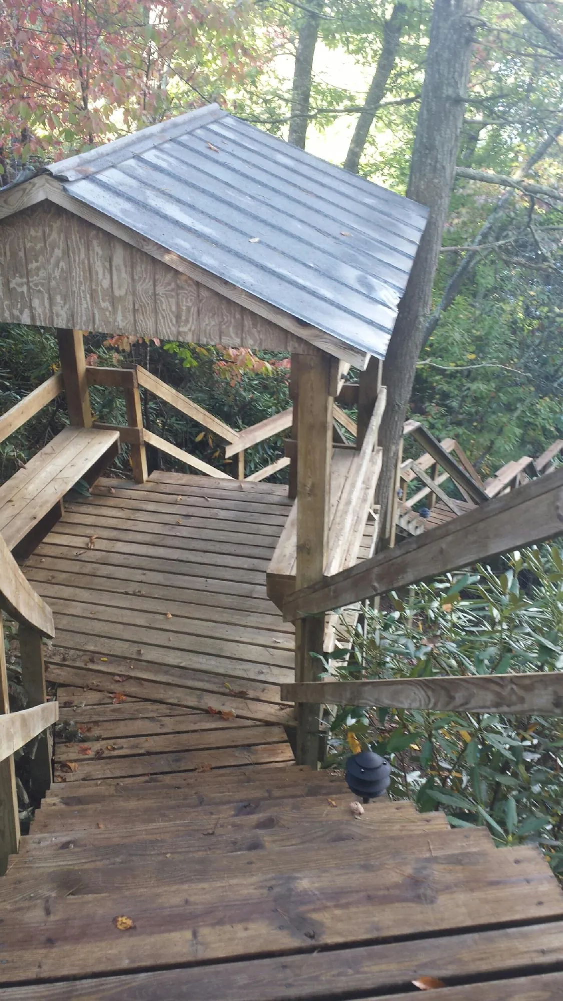 Metal roofed shelter over wooden steps on a wooded walkway — Skylight Repair & Installation work by our crew in Walled Lake