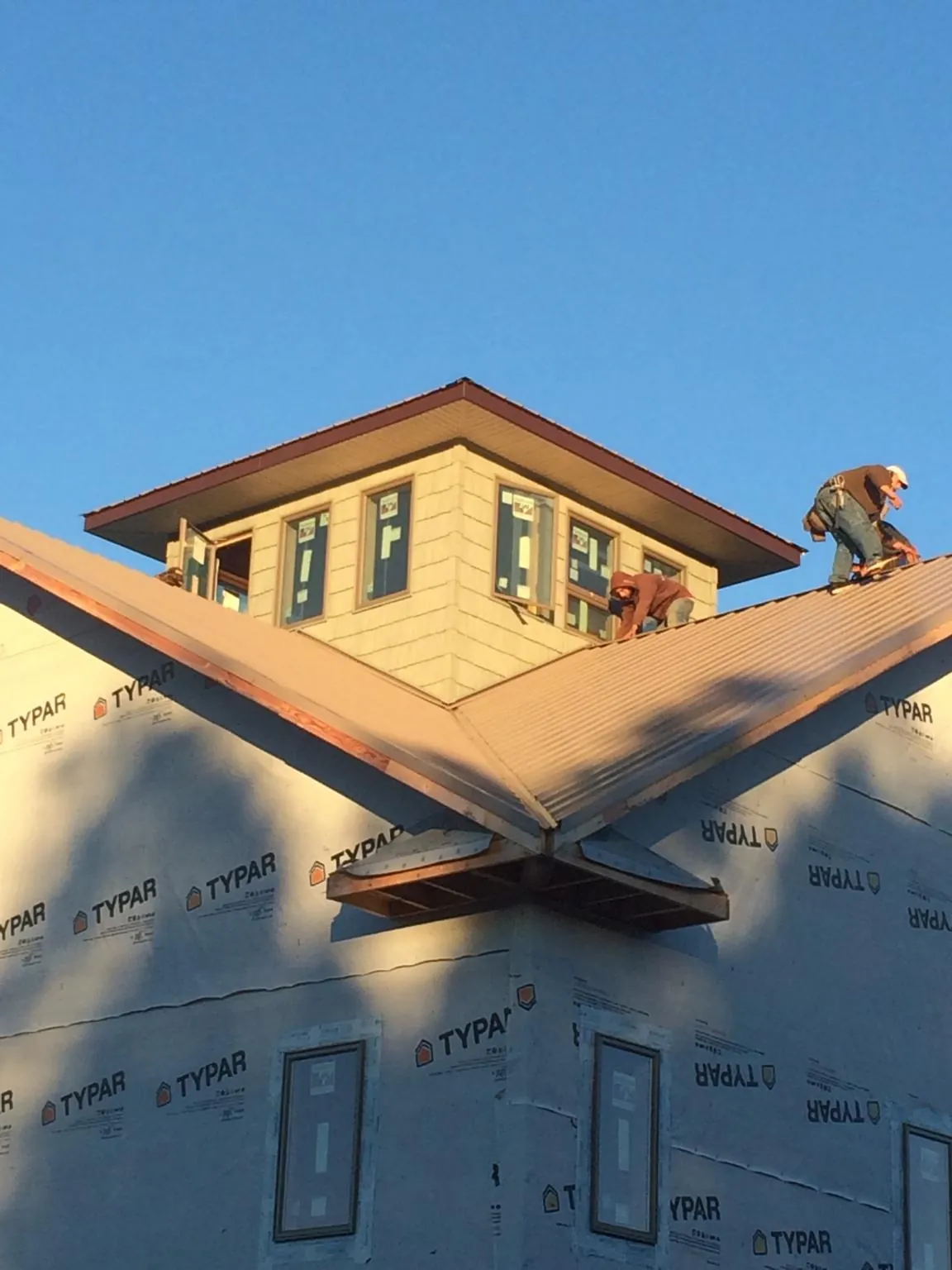 Roofers working around a rooftop cupola on a new metal roof at sunset — Roof Waterproofing in Walled Lake by Roofing Brothers